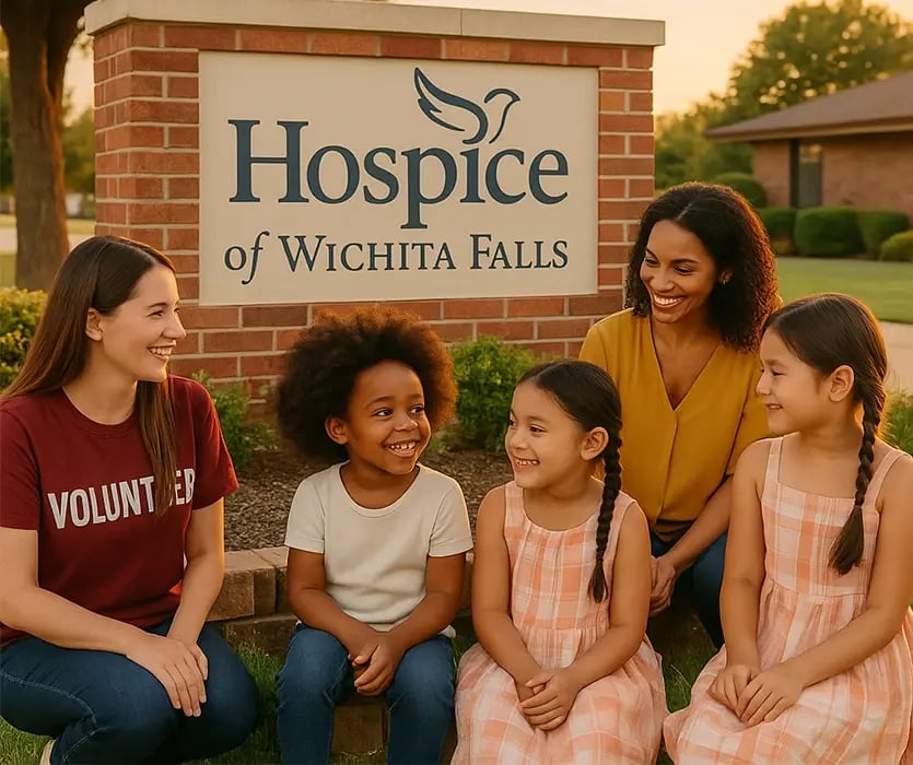 Volunteers and children gather outside Hospice of Wichita Falls, smiling together near the hospice sign, symbolizing community and care.